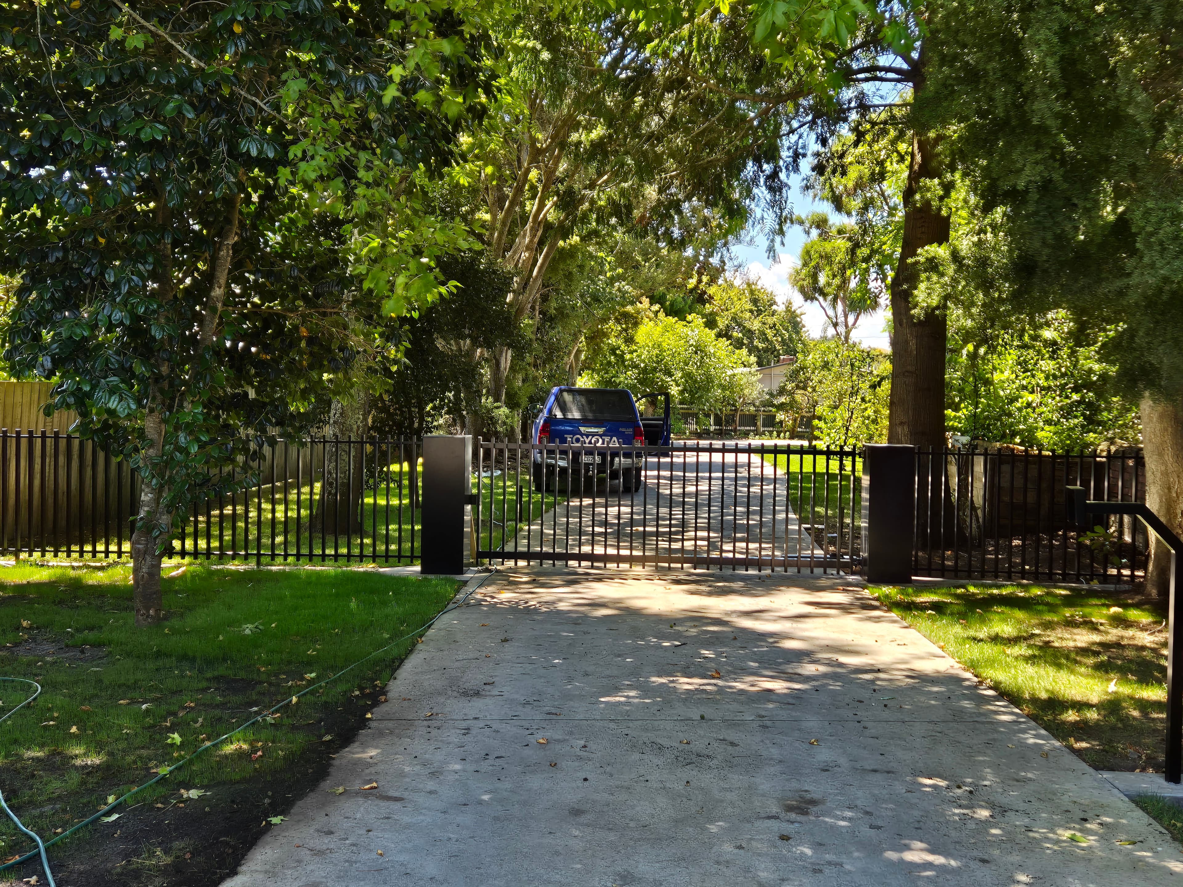 Black sliding driveway gate and fence line